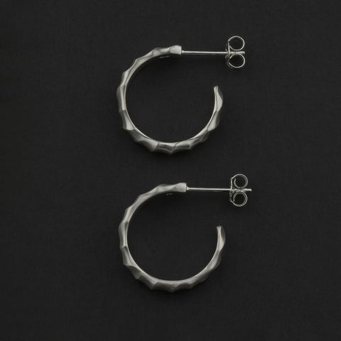 Pair of silver hoop earrings on a black background
