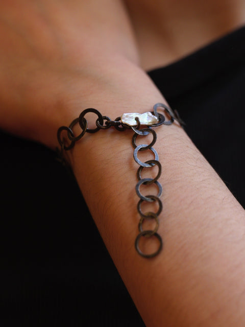 Close-up of a chain bracelet on a wrist with a blurred background