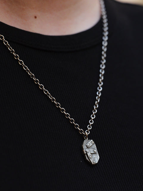 Silver chain necklace with a pendant worn over a black t-shirt
