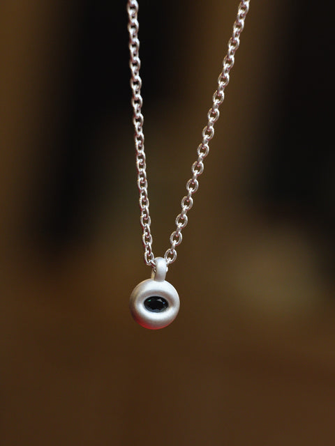 Silver necklace with a small marquise sapphire pendant on a blurred background