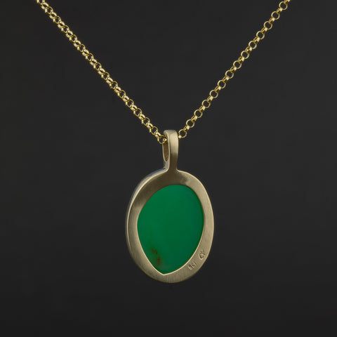 Gold necklace with a green chrysoprase pendant on a black background