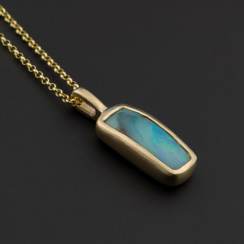 Opal and gold pendant on black background