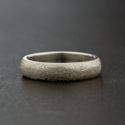 Silver ring with a textured surface on a dark background