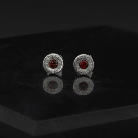 Pair of silver earrings with red gemstones on a black background